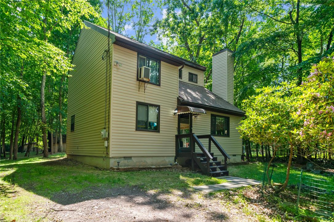 222 Powder Horn Road Henryville, PA 18332 - Photo 2 of 25 A private wooded setting surrounds this charming home with vinyl siding and dark trim, offering quiet retreat.