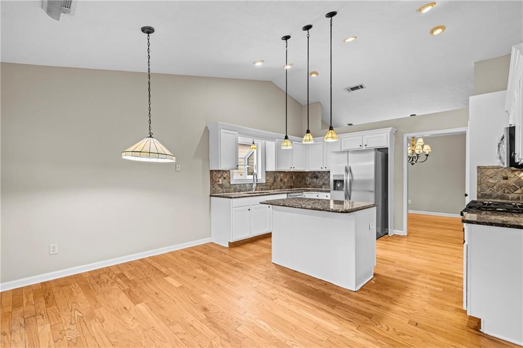 3360 Ennfield Lane Duluth, GA 30096 - Photo 10 of 38 a kitchen with stainless steel appliances granite countertop a sink a stove a refrigerator and island with wooden floor
