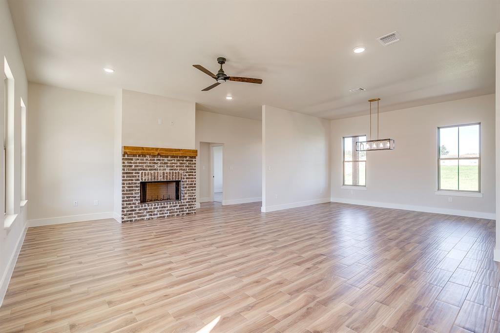 217 Kilkenny Road Poolville, TX 76487 - Photo 11 of 40 an empty room with wooden floor fireplace and windows