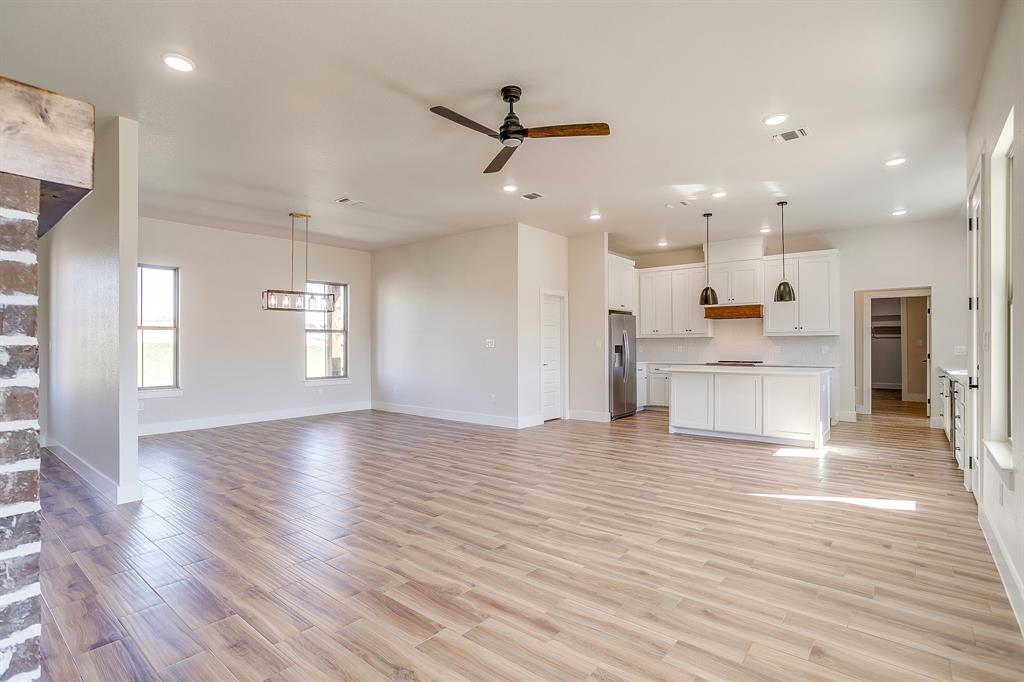 217 Kilkenny Road Poolville, TX 76487 - Photo 4 of 40 a view of an empty room and kitchen with wooden floor