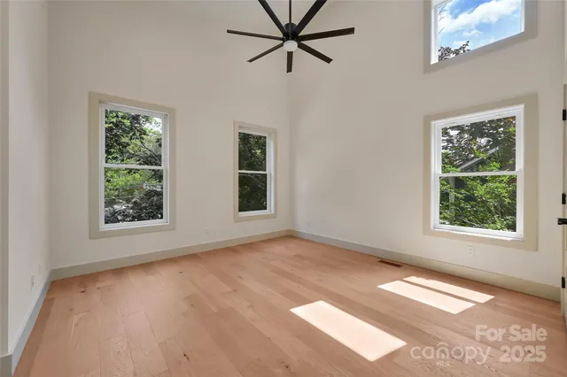 an empty room with wooden floor closet and windows