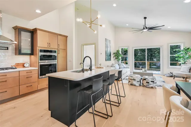 a kitchen with a stove a sink dishwasher a dining table and chairs with wooden floor