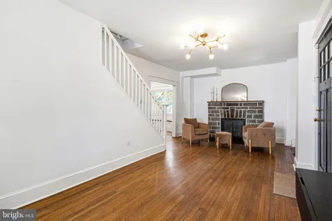 a view of a livingroom with furniture wooden floor chandelier and a window