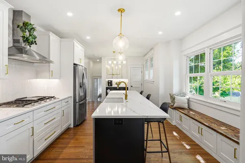 a large kitchen with kitchen island a sink a stove and a large window with wooden floor