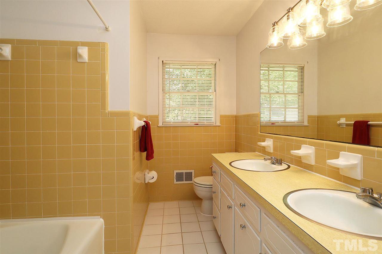 5027 Winterlochen Road Raleigh, NC 27603 - Photo 17 of 25 a bathroom with a granite countertop double vanity sink a mirror and a bathtub