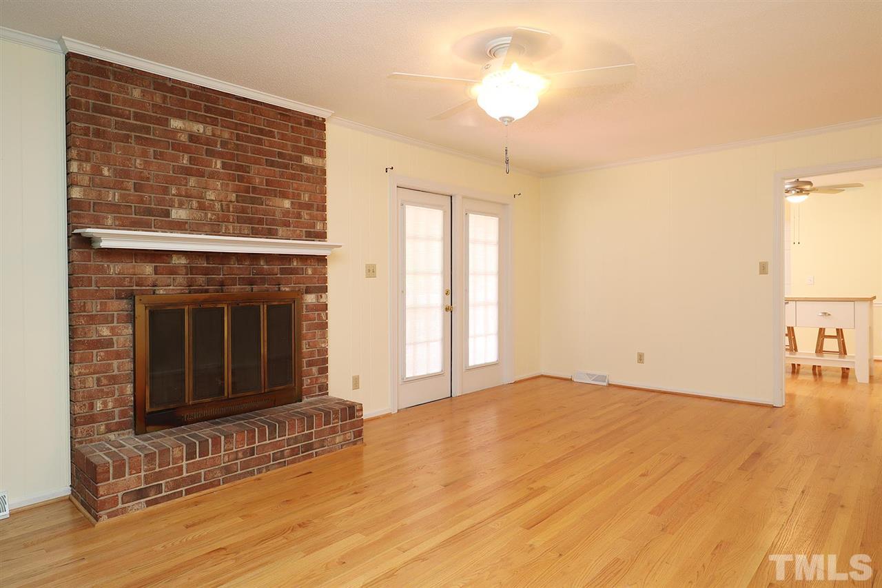 5027 Winterlochen Road Raleigh, NC 27603 - Photo 10 of 25 a view of empty room with wooden floor and fireplace