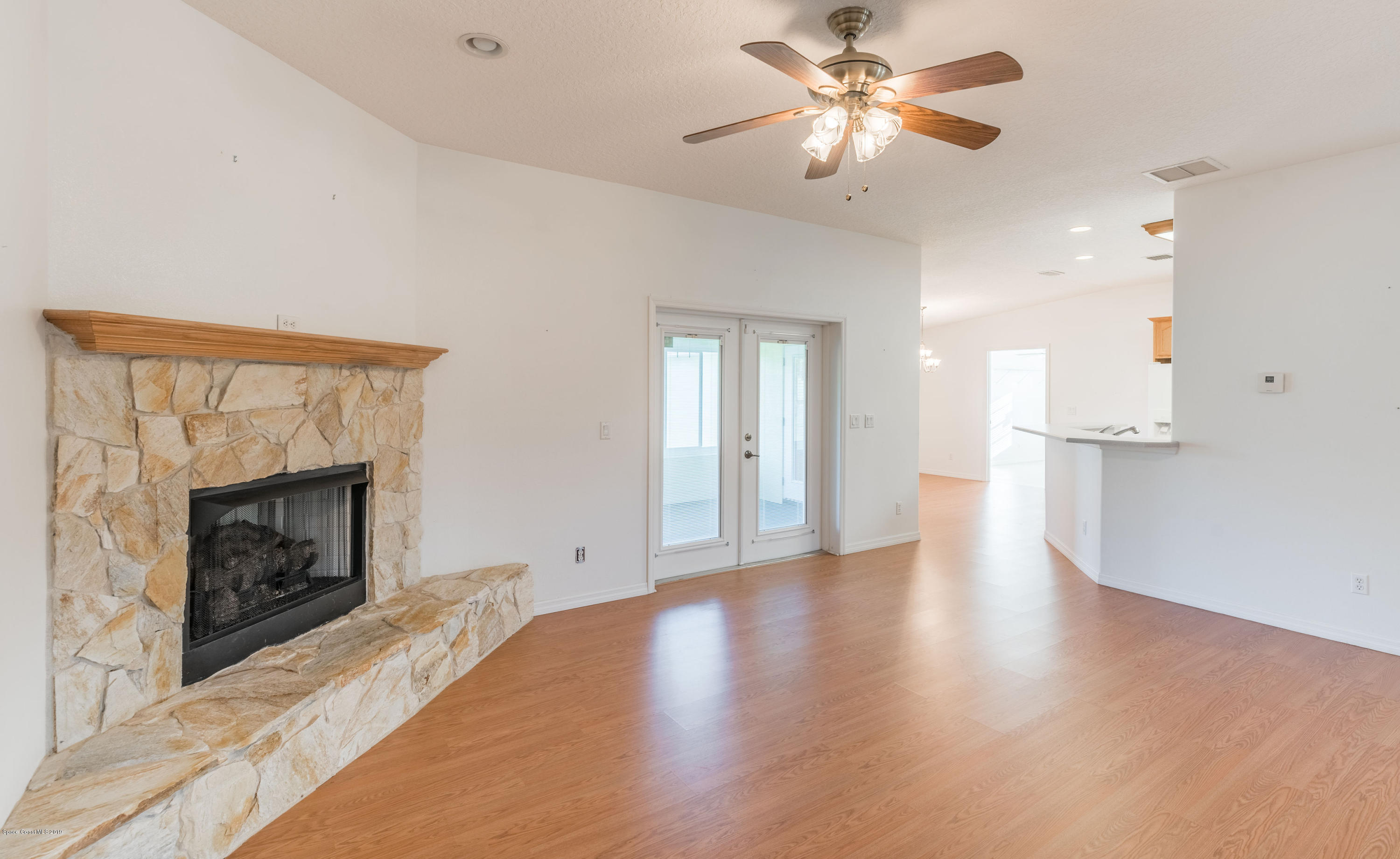 3700 Grant Line Road Mims, FL 32754 - Photo 14 of 40 a view of a kitchen with a fireplace a ceiling fan and wooden floor