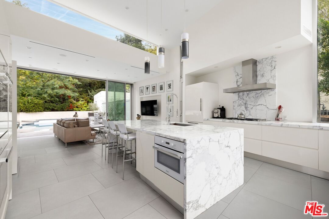 2654 Roscomare Road Los Angeles, CA 90077 - Photo 7 of 29 a kitchen with stainless steel appliances kitchen island granite countertop a sink and white cabinets