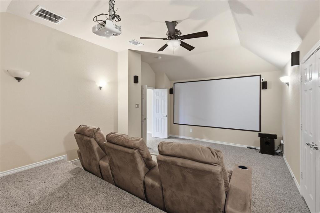 Home theater with lofted ceiling, carpet flooring, and ceiling fan