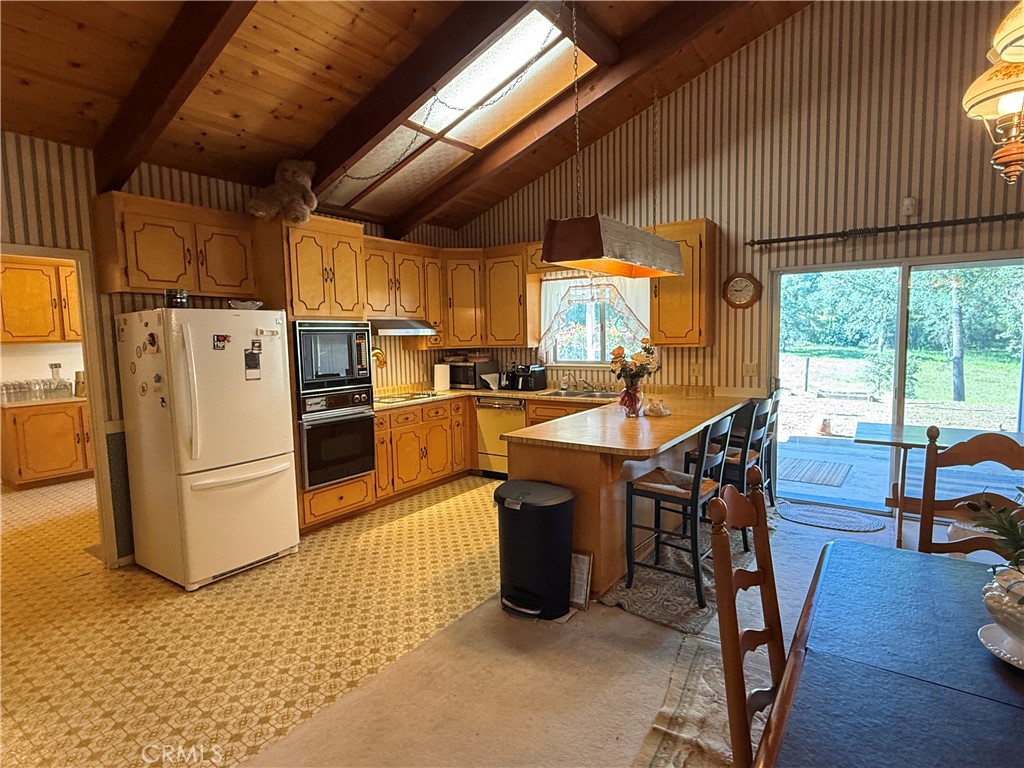 4952 Hidden Springs Road Mariposa, CA 95338 - Photo 21 of 53 a kitchen with stainless steel appliances a stove a refrigerator a dining table and chairs with wooden floor