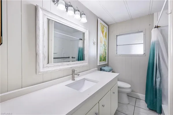 a bathroom with a granite countertop sink vanity mirror and toilet