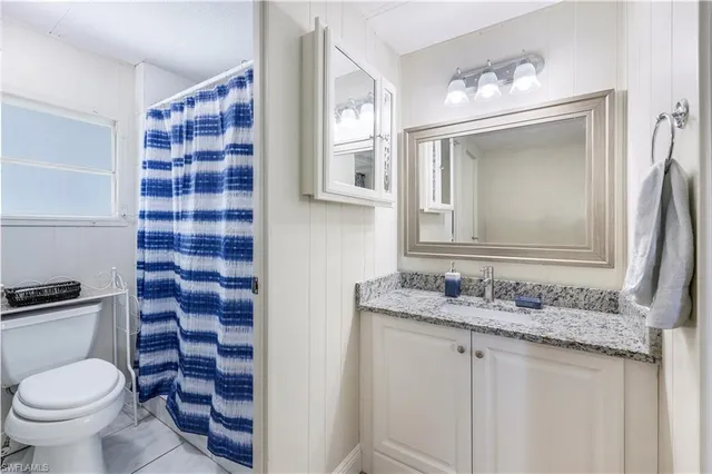 a bathroom with a granite countertop toilet a sink and a mirror