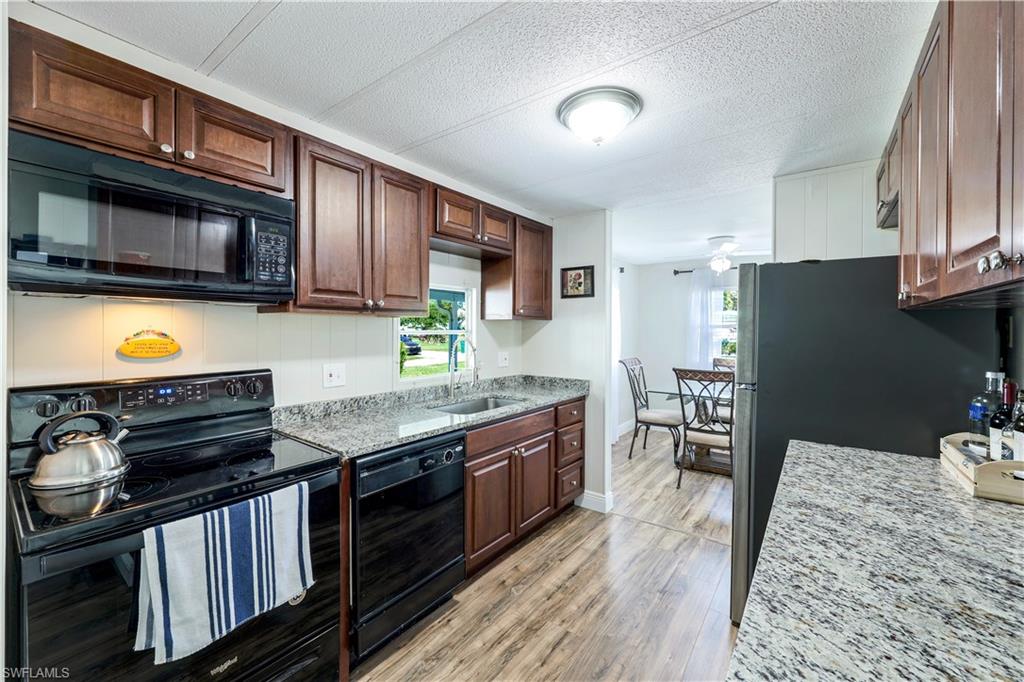 21 Lemans Drive Naples, FL 34112 - Photo 8 of 26 a kitchen with stainless steel appliances granite countertop a stove top oven a sink dishwasher and a refrigerator with wooden cabinets