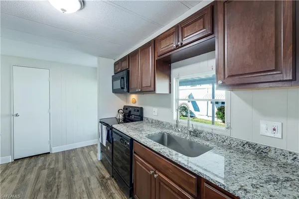 a kitchen with granite countertop a sink a stove and cabinets