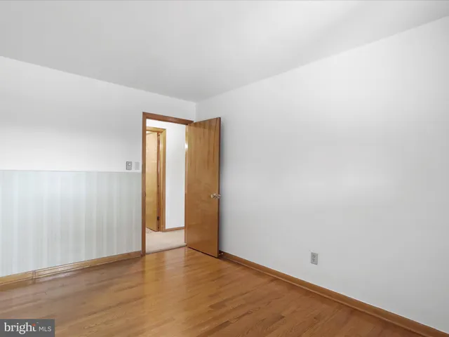 a view of an empty room with wooden floor and closet