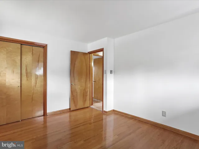 a view of an empty room with wooden floor and closet