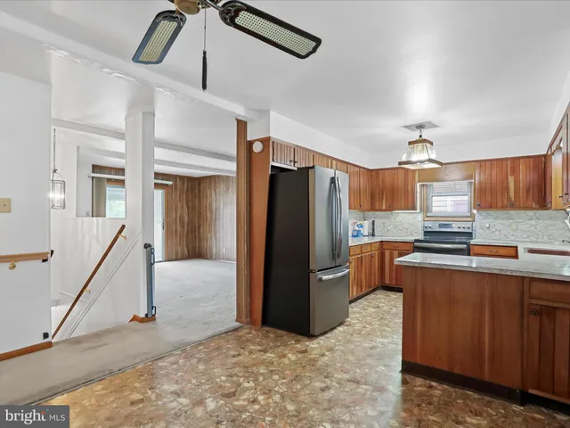 a kitchen with stainless steel appliances kitchen island granite countertop a refrigerator and a sink