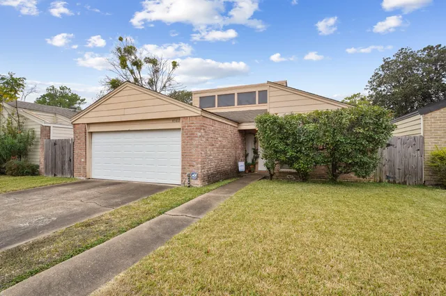 a front view of a house with a garden and garage