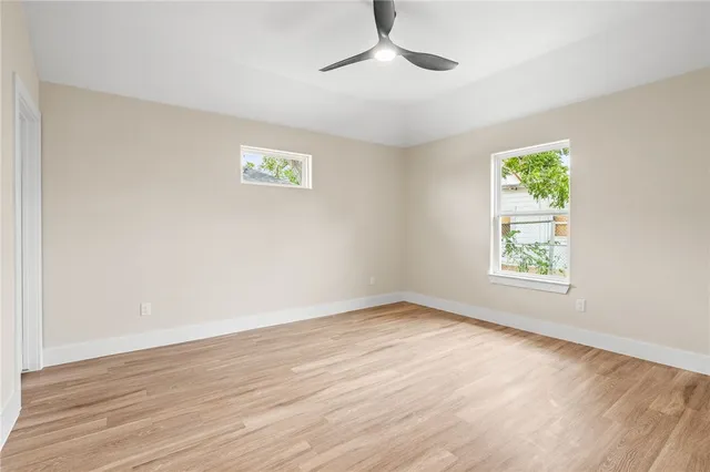 a view of an empty room with wooden floor and a window