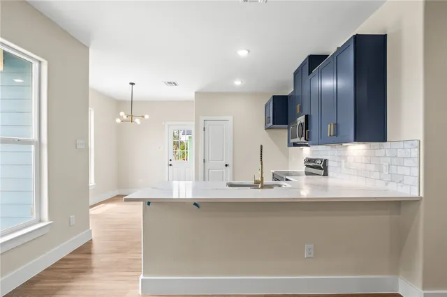 a view of kitchen with stainless steel appliances granite countertop kitchen island wooden floors and a view of living room