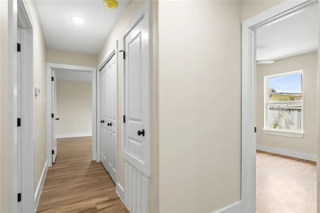 a view of a hallway with wooden floor and a bathroom
