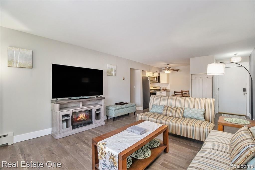 803 Plate Street, Unit 104 Rochester, MI 48307 - Photo 3 of 14 Open-concept living area featuring wood-finish flooring, TV table with built-in electric fireplace media console, and a contemporary lighting