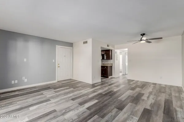 a view of an empty room with wooden floor and a window