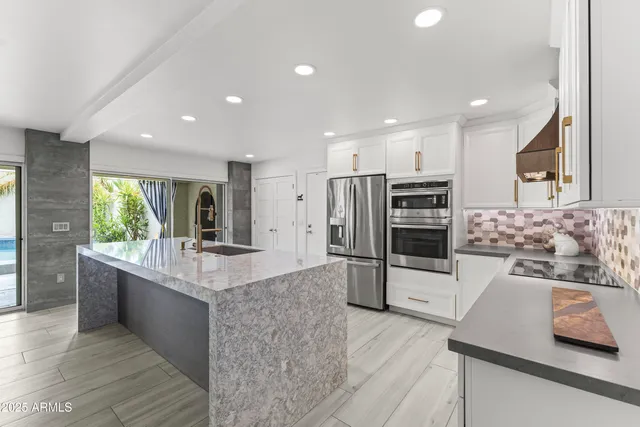 a large kitchen with stainless steel appliances kitchen island granite countertop a large counter top and a stove