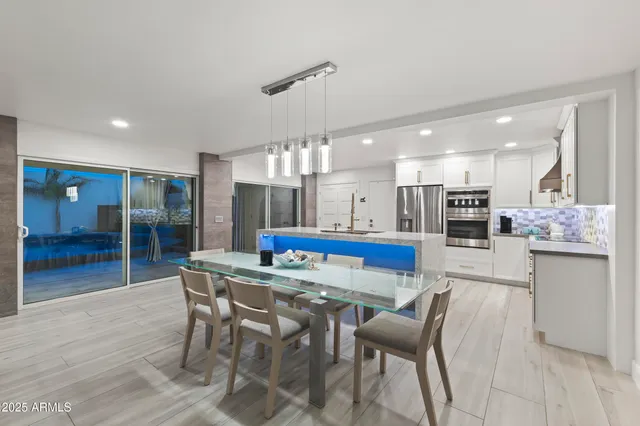 a kitchen with stainless steel appliances kitchen island granite countertop a dining table chairs and white cabinets