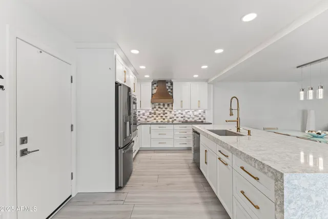 a large kitchen with a large counter top a sink and stainless steel appliances