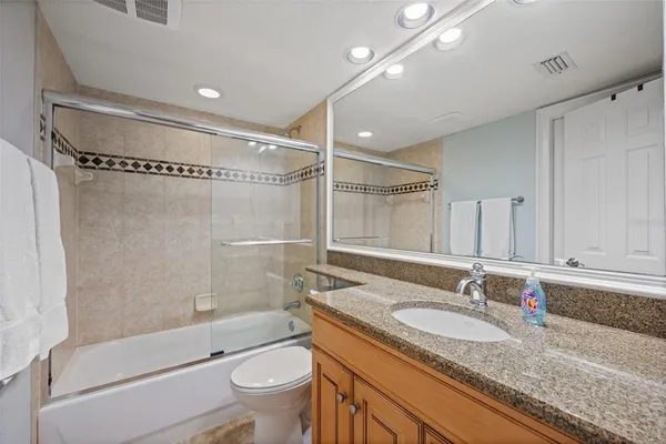 a bathroom with a granite countertop sink a toilet and shower
