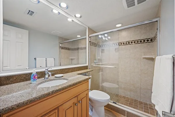 a bathroom with a granite countertop sink mirror vanity and toilet