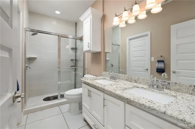 a bathroom with a granite countertop sink a toilet and shower