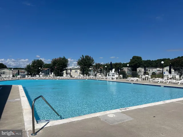 a view of a swimming pool with lawn chairs under an umbrella