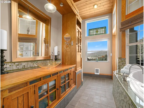 a bathroom with a tub a sink and a large window