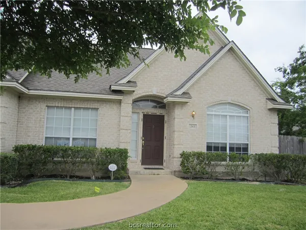 a view of a white house next to a yard with potted plants and large trees