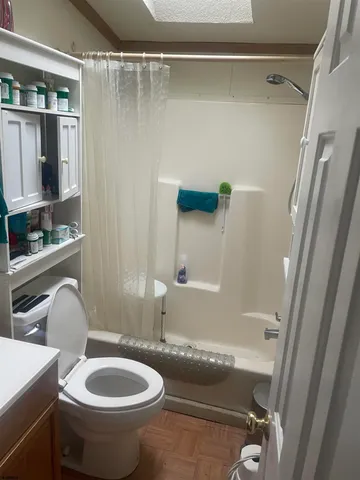 a bathroom with a granite countertop bathtub sink vanity mirror and toilet
