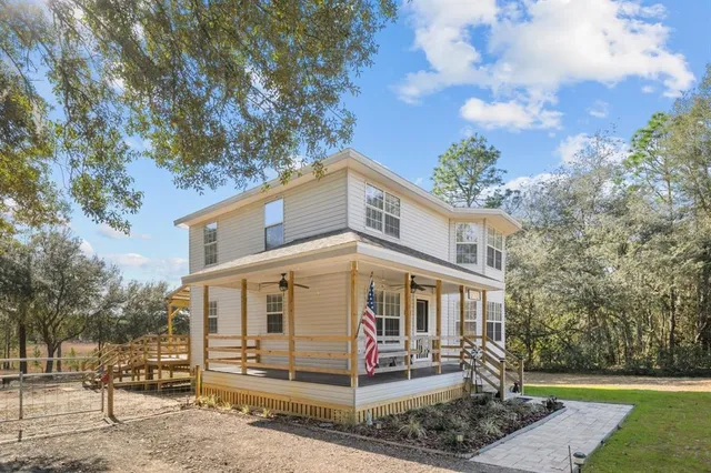 a view of a white house with large trees and a yard