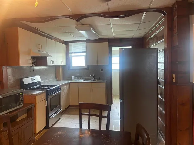 a kitchen with granite countertop a stove a refrigerator and wooden cabinets
