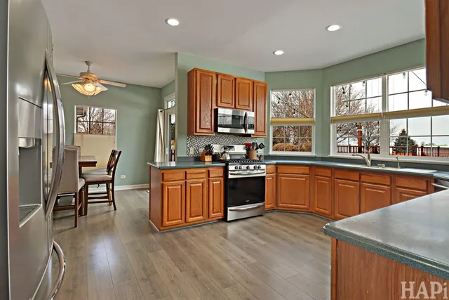 a kitchen with stainless steel appliances granite countertop wooden cabinets a stove a sink a dining table and chairs