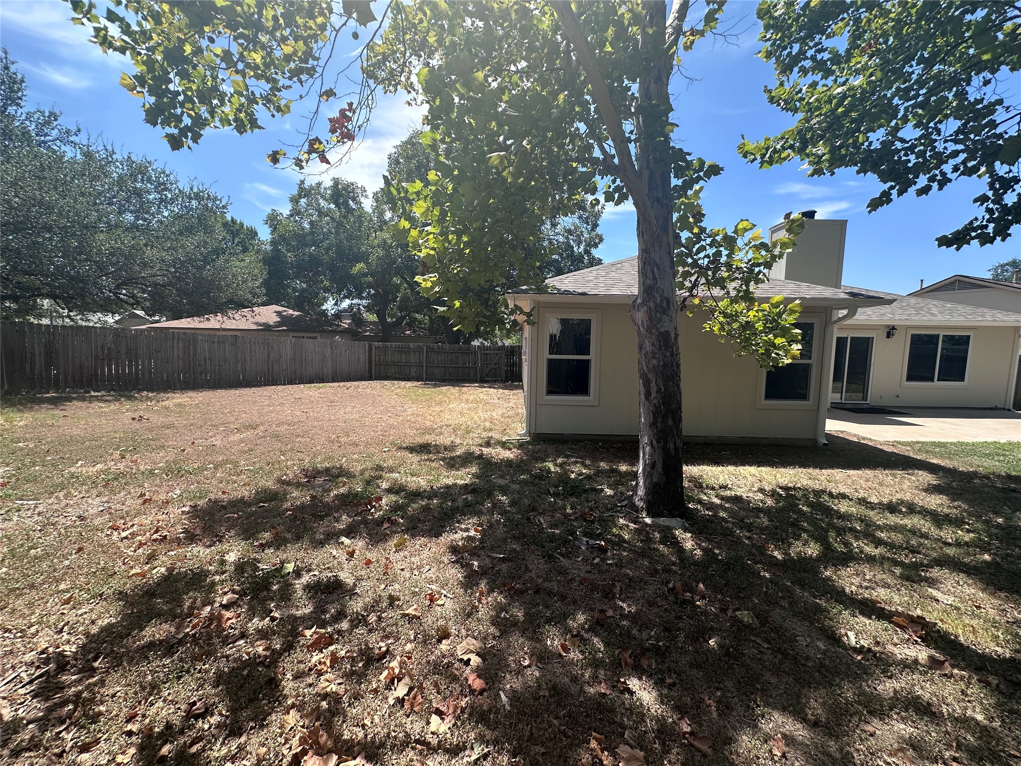 12610 Andromeda Cove Austin, TX 78727 - Photo 26 of 29 Mature shade trees frame a spacious lawn enclosed by a wooden privacy fence.