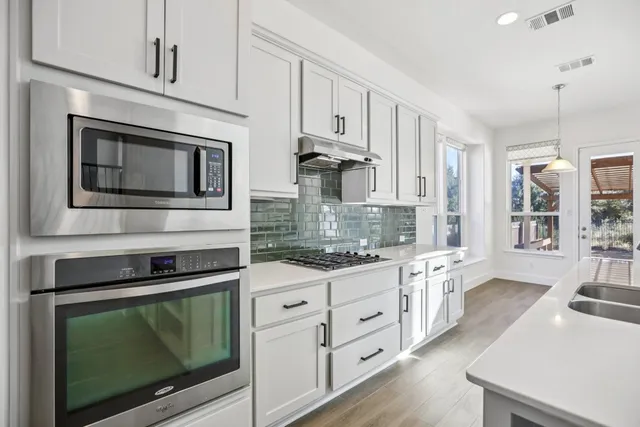 a kitchen with granite countertop cabinets stainless steel appliances and wooden floor