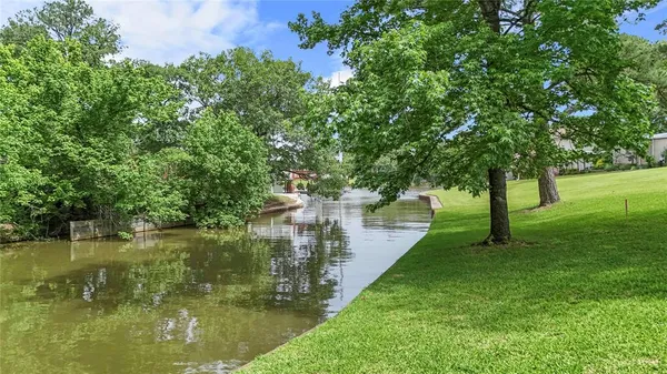 a view of a lake with a yard and large trees