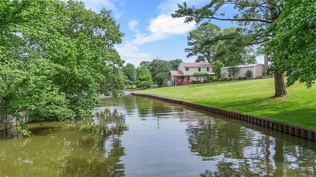 a view of a lake with a yard and large trees