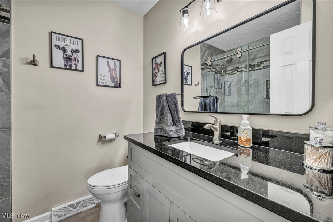 7662 State Road Wadsworth, OH 44281 - Photo 36 of 49 Full bathroom featuring a stall shower, toilet, vanity, wood finished floors, and baseboards