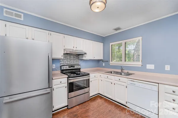 a kitchen with a sink appliances cabinets and a window