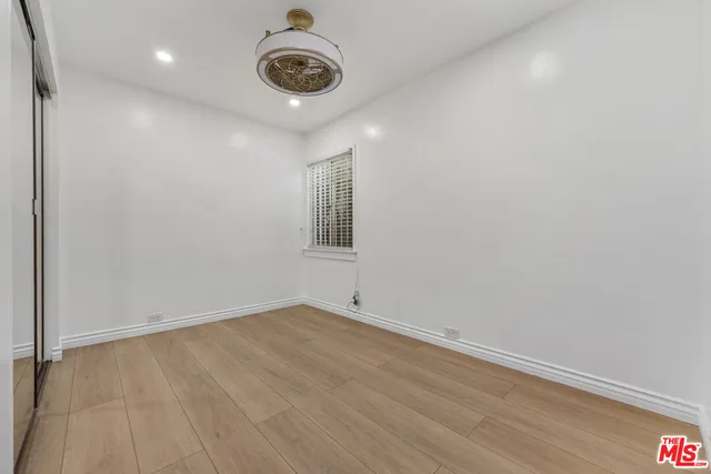 an empty room with a ceiling fan and wooden floor