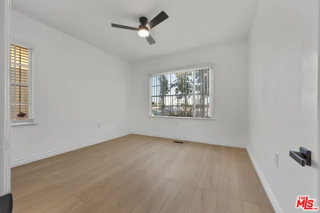 an empty room with wooden floor ceiling fan and windows