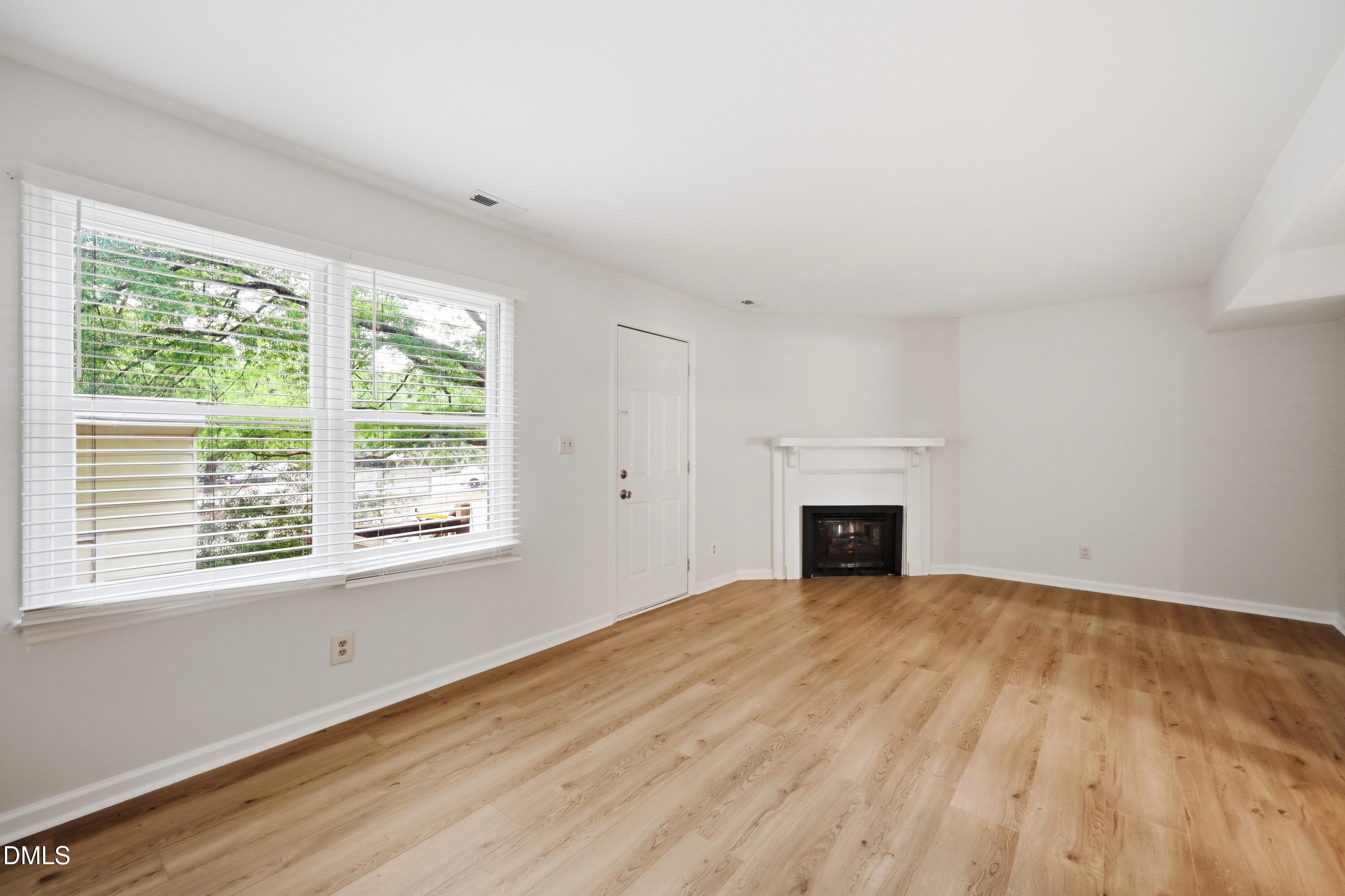 669 Bashford Road Raleigh, NC 27606 - Photo 6 of 19 a view of empty room with wooden floor and fireplace