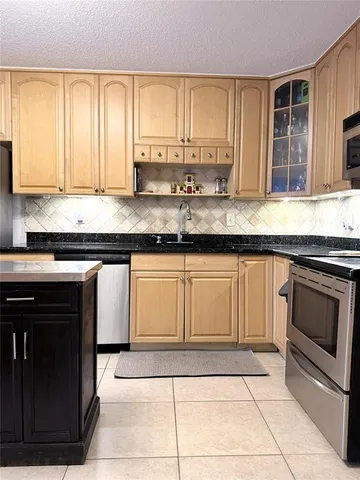 a kitchen with granite countertop a sink a stove and cabinets